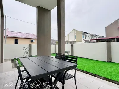 a wooden table and chairs on a patio with grass at BBC Play Ipoh Homestay in Ipoh