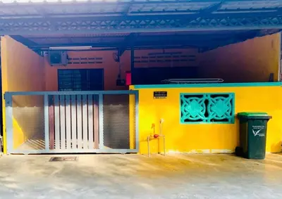a yellow building with a gate and a trash can at Homestay Hayyan