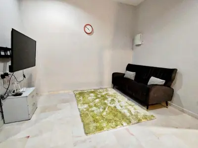 a living room with a black couch and a tv at Ipoh FamilyHub by One Life Four Season Guesthouse in Ipoh