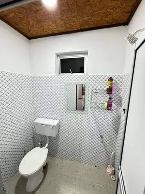 a white bathroom with a toilet and a window at Damai Homestay in Gua Sai