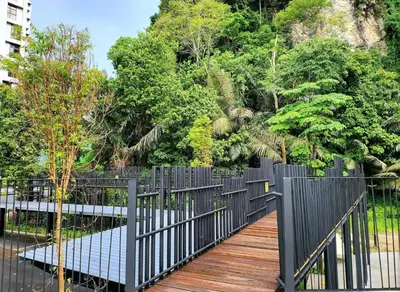 a wooden walkway with a black fence and trees at Ipoh The Cove Hillside Premier Suites By LUX SUITE in Ipoh