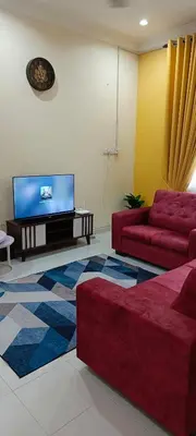 a living room with two red couches and a flat screen tv at ANAS Inn Homestay Balik Pulau, Penang in Balik Pulau
