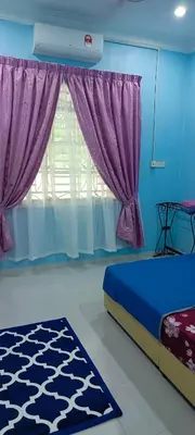 a bedroom with a bed and a window with purple curtains at ANAS Inn Homestay Balik Pulau, Penang in Balik Pulau