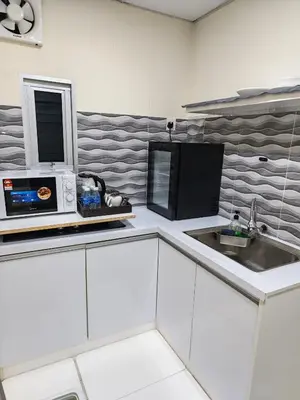 a white kitchen with a microwave and a sink at Qalsharyna Chalet inn in Simpang