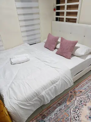 a large bed with white sheets and purple pillows at Qalsharyna Chalet inn in Simpang