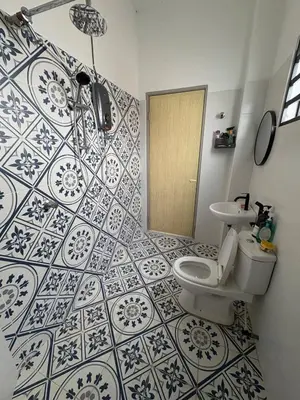 a bathroom with a toilet and a tile wall at Luxury House Panoramic Views and Elegant Comfort in Batu Gajah