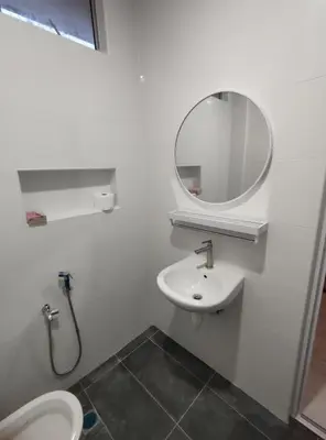 a white bathroom with a sink and a mirror at Sweet Home in Balik Pulau