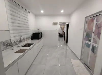 a white kitchen with a sink and a hallway at Sweet Home in Balik Pulau