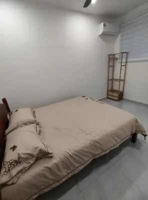 a bed in a room with a white wall at Sweet Home in Balik Pulau