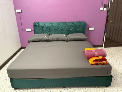 a bed with a green headboard and a purple wall at 786 Bali Top Homestay in Sungai Petani