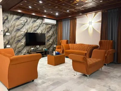 a waiting room with orange chairs and a flat screen tv at 786 Bali Top Homestay in Sungai Petani