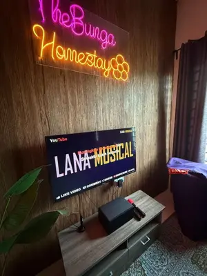 a tv on a wall with a sign and a table at TheBunga Homestay w Private Pool&Karaoke -Tronoh Perak in Teronoh