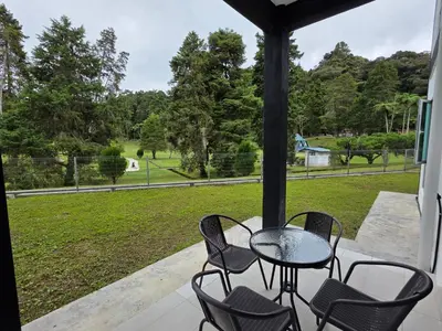 a table and chairs on a porch with a view of a park at Teeview Homes in Tanah Rata