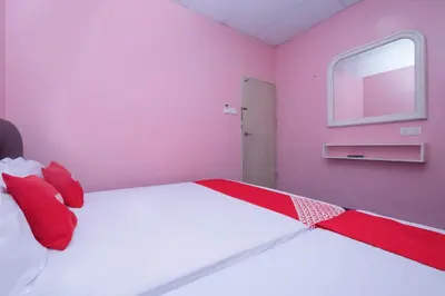 a pink bedroom with a large bed with red pillows at OYO 89984 Noris Wang Homestay in Kampong Banjar