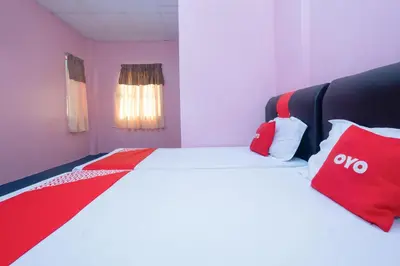 a bedroom with a bed with red and white pillows at OYO 89984 Noris Wang Homestay in Kampong Banjar