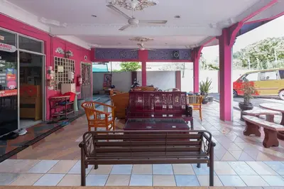 a red room with a bench and tables and chairs at OYO 89984 Noris Wang Homestay in Kampong Banjar