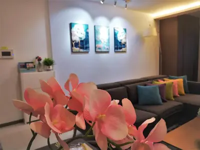 a living room with a couch and pink flowers at Premier Suite Seaview 3 minute to gurney in Gua Sai