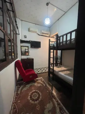 a room with a red chair and a bunk bed at Pearl Heritage Guesthouse in George Town