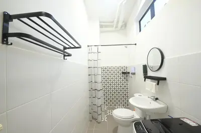 a white bathroom with a toilet and a sink at Yeop & Chor Homestay in Seri Iskandar