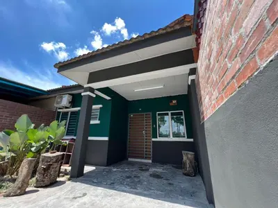 a house with a green front door and a brick wall at Adila Homestay in Seri Iskandar