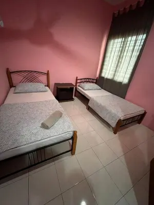 two beds in a room with pink walls at Adila Homestay in Seri Iskandar