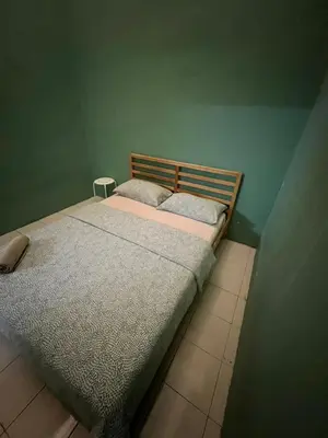 a bed in a green room with two pillows on it at Adila Homestay in Seri Iskandar