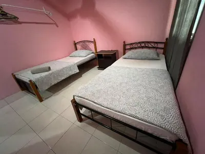 two beds in a room with pink walls at Adila Homestay in Seri Iskandar