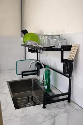 a kitchen sink with a faucet and dishes on a shelf at 525A Homestay Malim Nawar in Malim Nawar