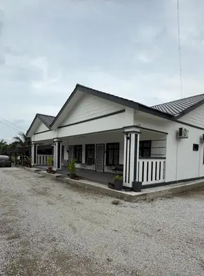a white house with a car parked in the driveway at De Bagan Village, Tanjong Karang in Tanjung Karang