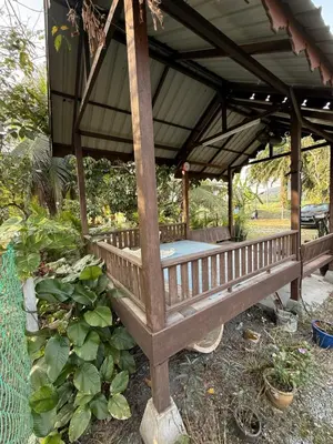 a wooden gazebo in a garden with plants at Laman Warisan Opah Homestay in Manong