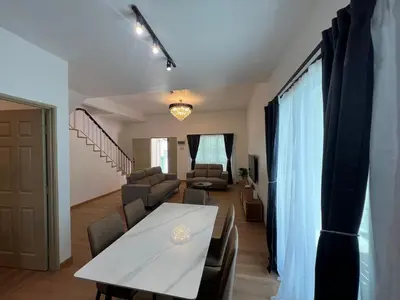 a dining room and living room with a table and chairs at Rumah by Abg K in Cameron Highlands in Tanah Rata