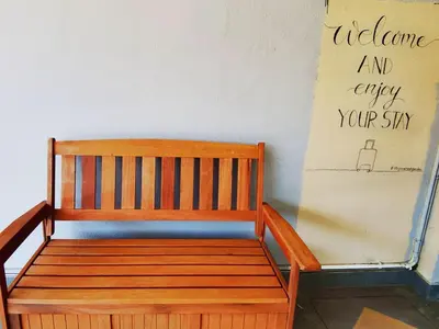 a wooden bench sitting next to a wall with a sign at Spacious 4BR Corner with Pool Table in Ipoh