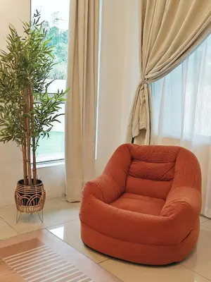 an orange chair in a living room with a plant at 16 Paxx Mountain Joy Corner Villa with KTV Pool BBQ in Ipoh