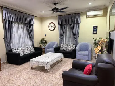 a living room with couches and a table and a clock at Bidor Bonda Homestay in Bidur