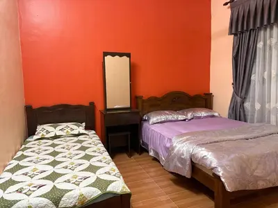 two beds in a room with orange walls and a mirror at Bidor Bonda Homestay in Bidur