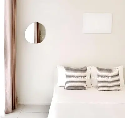 a white bedroom with a bed with a mirror at The Urban Suites City&seaview in Jelutong