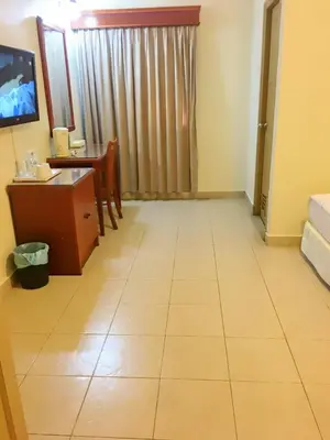 a hotel room with a desk and a table and a room at Harbour View Hotel Sekinchan in Sekincan