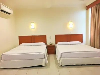 two beds in a hotel room with white sheets at Harbour View Hotel Sekinchan in Sekincan