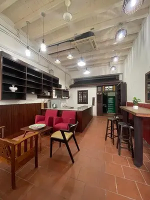 a living room with red chairs and a kitchen at Pearl Heritage Homestay in George Town
