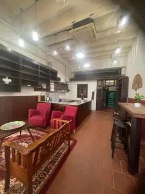 a living room with red chairs and a kitchen at Pearl Heritage Homestay in George Town