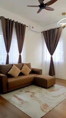 a living room with a brown couch and curtains at Risfeena Home in Sekincan