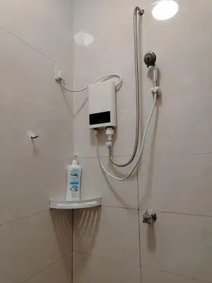 a shower in a bathroom with a hand dryer on the wall at Risfeena Home in Sekincan