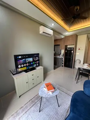 a living room with a tv and a couch and a table at Modern Two Bedroom Ipoh City Apartment with Pool, Gym and Free Parking in Ipoh