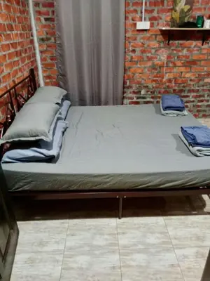 a bed sitting in a room next to a brick wall at Homestay Anjang in Tapah