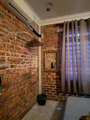 a room with a brick wall and a mirror at Homestay Anjang in Tapah