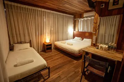 a bedroom with two beds and a desk with a mirror at Joe Fisherman Inn in Pangkor