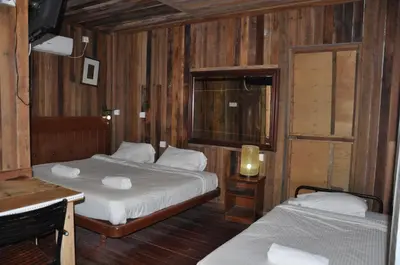 a room with two beds and a table with a lamp at Joe Fisherman Inn in Pangkor
