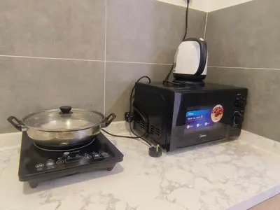 a pan on top of a microwave next to a toaster oven at The Cove Signature Hillside Ipoh by MW in Ipoh