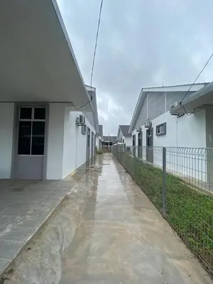 a wet sidewalk next to a white building with a fence at HSKeladanImpian in Gua Sai