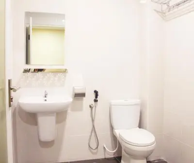 a white bathroom with a toilet and a sink at No.31 Maple Inn in Simpang Ampat